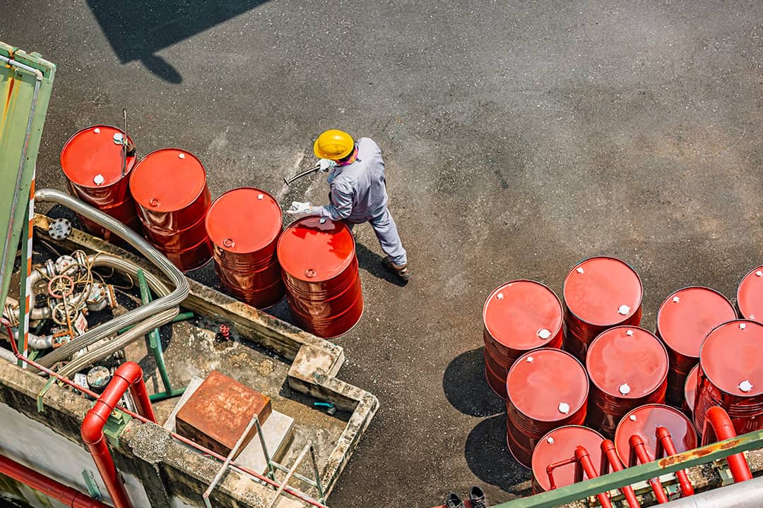 Top view of a male worker checking barrels of oil.